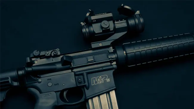A Smith & Wesson M&P 15 rifle with an attached optical sight, laid on a dark surface