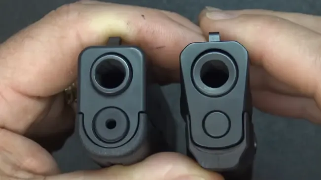 Front view comparison of the barrels of a Glock 43 and S&W Shield 9mm pistol held side by side.