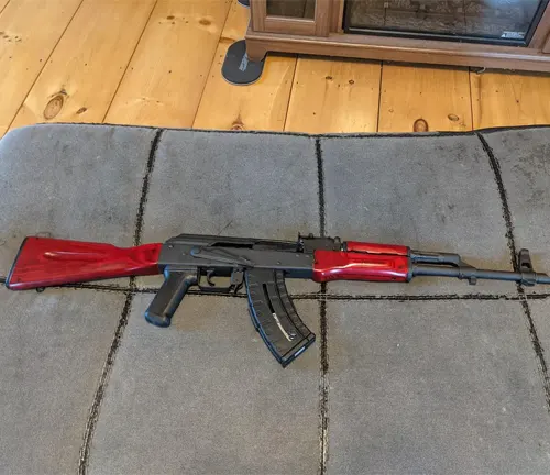 A Century Arms WASR-10 rifle with red furniture on a grey couch
