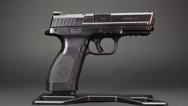 A black EAA Girsan MC28 SA pistol displayed on a stand, showcasing its sleek design with a clear view of the slide, barrel, and ergonomic grip against a gradient gray background.