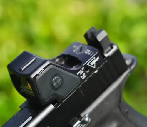 Close-up of the rear sight on a Glock pistol, with a focus on the adjustable sight mechanism and the blurred greenery in the background.