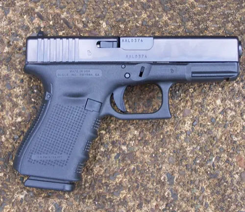 A Glock 48 pistol with a two-tone design, featuring a black polymer frame and a contrasting silver-colored slide, resting on a gravel surface.