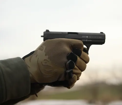 A person's gloved hand holding an HK P7 PSP pistol.