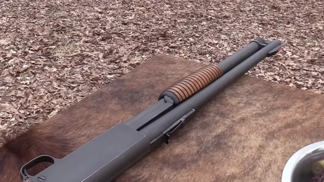 Ithaca Model 37 pump-action shotgun with a blued finish and wooden forend, lying on a fur rug over a leafy ground.