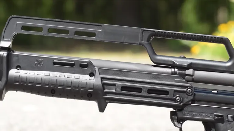 Side view of a Kel-Tec KSG shotgun with dual magazine tubes and an integrated carry handle against a blurred natural background.