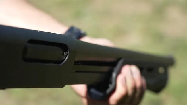 Close-up of a Remington Tac-14's ejection port and fore-end in hand, with a blurred background.