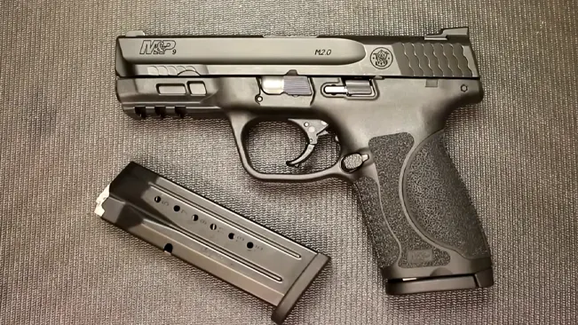 S&W M&P 2.0 Compact pistol with detached magazine on a textured background.