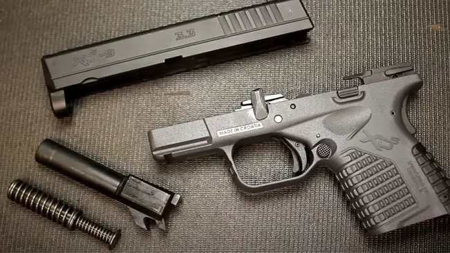 Springfield XD-S pistol partially disassembled with components laid out on a textured surface