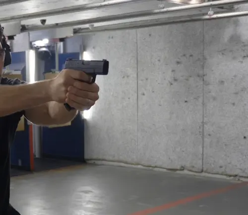 Person aiming a Springfield XD-S pistol at a target in an indoor shooting rang