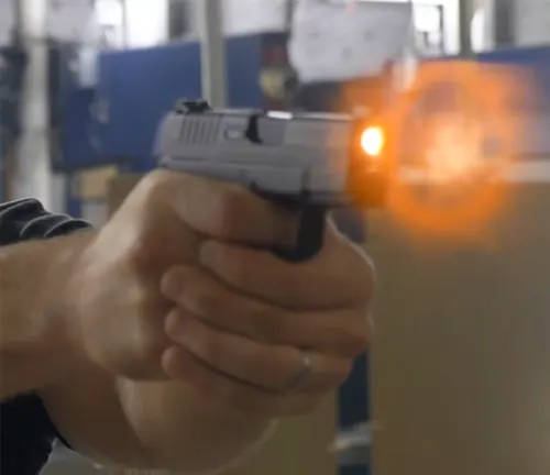 Person firing a Springfield XD-S handgun with muzzle flash visible