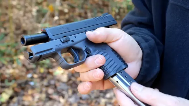 Hands loading a magazine into a Springfield XD-S handgun