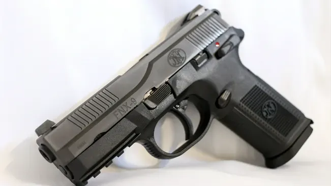 FN FNX-9 semi-automatic pistol with a black finish and red safety indicator, positioned at an angle on a white background.