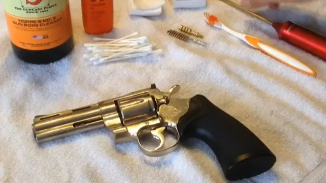 Colt Anaconda .44 Magnum revolver on a towel with cleaning supplies and brushes around it.