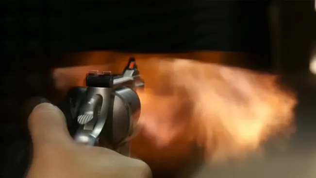 Smith & Wesson 627 revolver firing with muzzle flash visible, held in a person's hand.