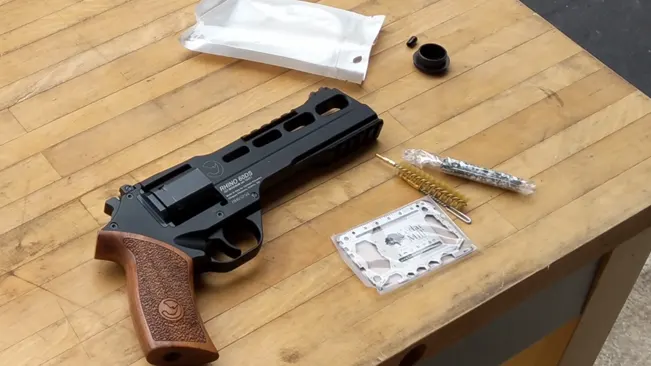 Chiappa Rhino revolver disassembled for cleaning on a wooden table with cleaning tools.
