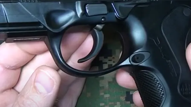 Close-up of a hand holding a Beretta PX4 Storm subcompact pistol, focusing on the trigger and guard area.