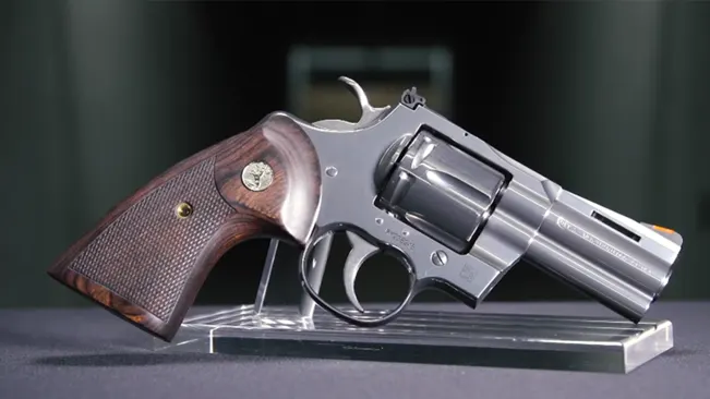 Colt Python 3-inch revolver displayed on a clear stand against a dark background.