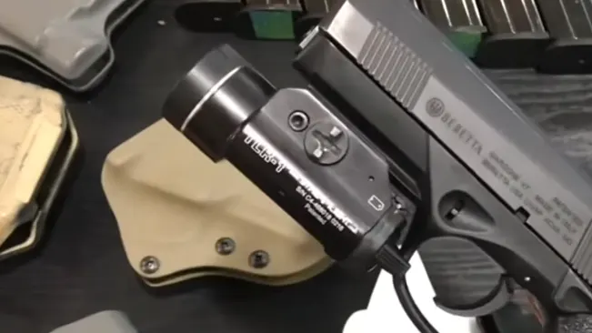 A Beretta PX4 Storm subcompact pistol with a mounted flashlight, resting on a tan holster.
