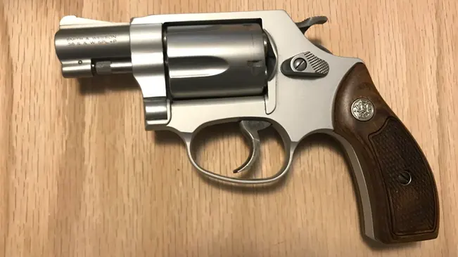 Smith & Wesson M637 revolver with wooden grip on a wooden table.