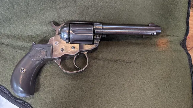 Colt 1877 Thunderer revolver with a long barrel on a green background.