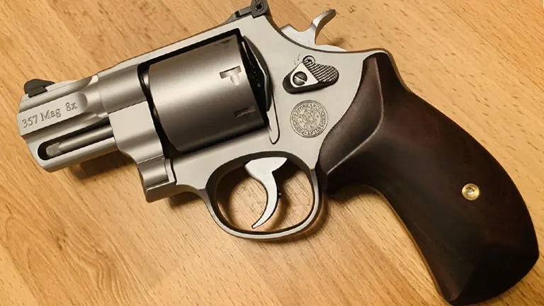 Smith & Wesson 627 revolver with a dark wooden grip and stainless steel frame on a wooden surface.