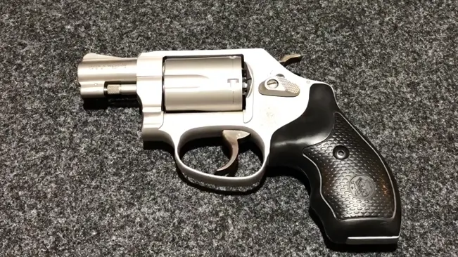 Smith & Wesson M637 revolver with black ergonomic grip on a speckled surface.