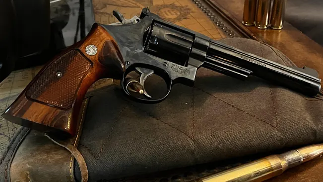 Smith & Wesson Model 19 revolver with a polished metal finish and wooden grip, resting on a fabric surface.