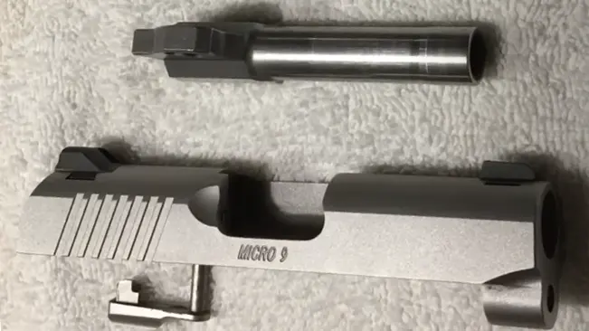 Disassembled Kimber Micro 9, showing slide and barrel, on a textured surface.