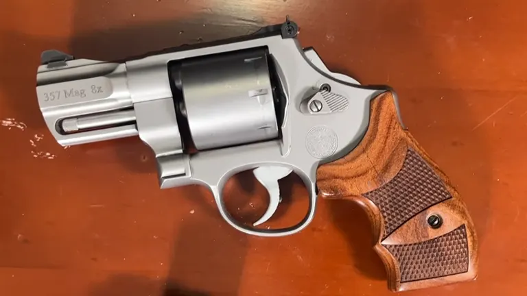 Smith & Wesson 627 revolver on a wooden surface, featuring a stainless steel barrel and a textured wooden grip.