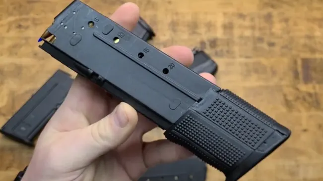 Hand holding an FN Five-SeveN pistol magazine loaded with cartridges.