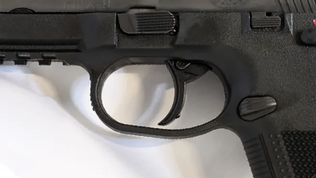 Close-up view of the FN FNX-9's trigger and trigger guard against a white background.