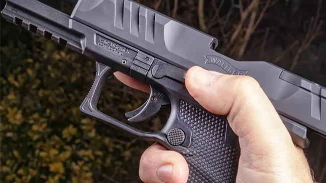 Close-up of a hand holding a Walther P99 pistol with a focus on the trigger and grip