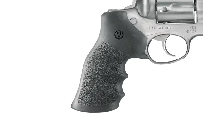 Partial view of a stainless steel Ruger GP100 revolver, focusing on the textured grip and serial number.