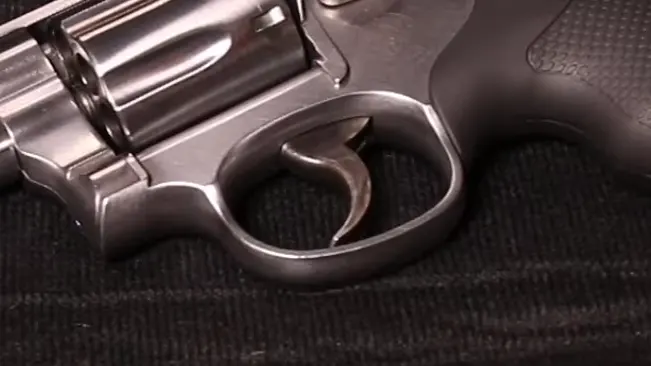 Detailed view of the trigger and cylinder release of a Smith & Wesson 686 revolver on a textured surface.