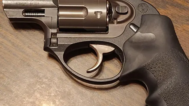 Close-up of a Ruger LCR revolver trigger and cylinder on a wooden surface.