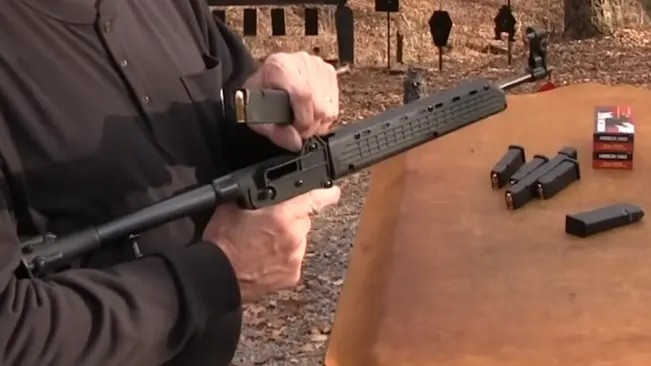 Person loading a magazine into a Kel-Tec SUB-2000 rifle on a shooting range