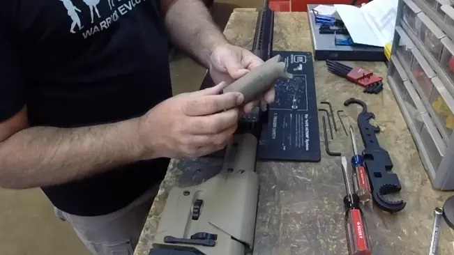 Person assembling a Ruger Precision Rifle on a workbench with tools and parts laid out
