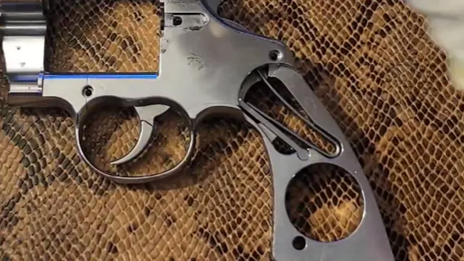 Disassembled frame of a Colt Anaconda .44 Magnum revolver on a textured background.