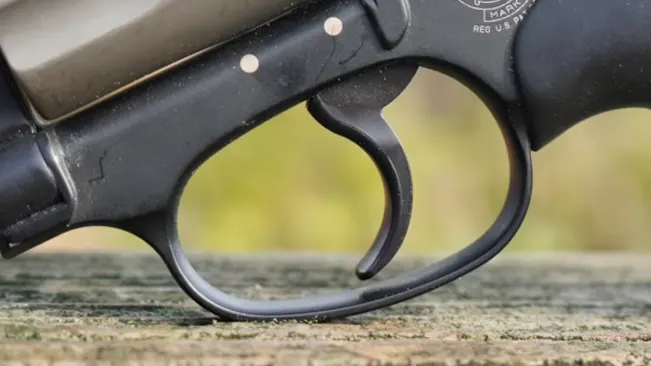  Close-up of the trigger and trigger guard on a Smith & Wesson J-Frame 340 PD revolver, set against a natural backdrop.