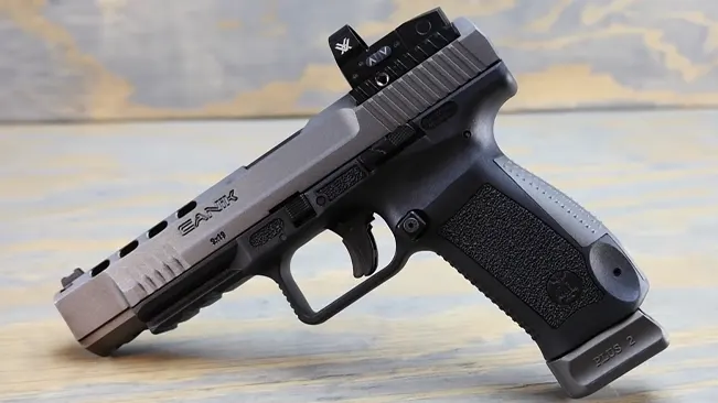 Canik TP9SFX handgun with a black grip and desert tan slide, resting on a wooden surface