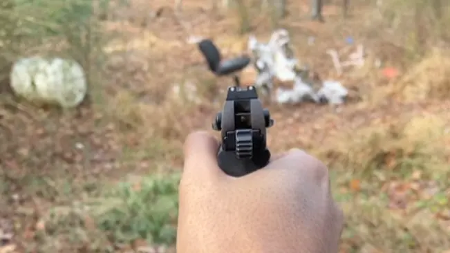 First-person view of a person aiming a Walther PK380 pistol, with focus on the rear sight.