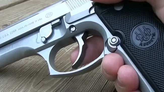 Close-up of a hand pulling the trigger on a Beretta 92FS INOX pistol with distinctive black grips and branding.