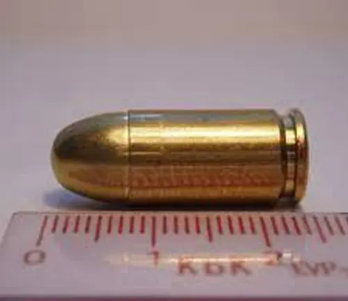 A 9mm Luger cartridge placed next to a ruler for scale, potentially used in firearms like the Beretta PX4 Storm subcompact.
