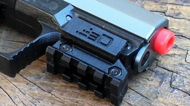 Close-up of a Walther P99 handgun with an attached laser sight and red safety tip