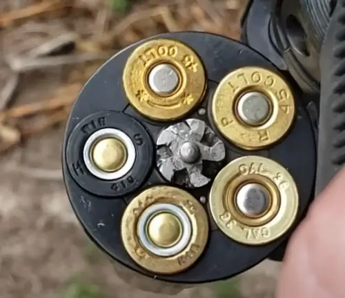 Close-up of the loaded cylinder of a Taurus Judge Public Defender 2 revolver, showing various ammunition.