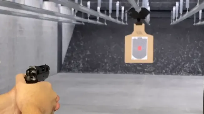 A shooter's point of view aiming a CZ-75 PCR pistol at a target in a shooting range.