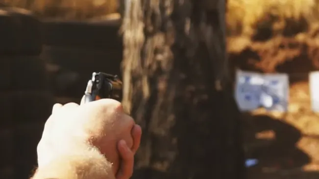 Hand holding an Astra 680 revolver aimed at a target in a blurred outdoor setting.