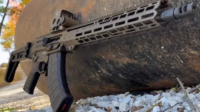 CMMG Dissent MK47 rifle propped against a rock, showcasing its unique design and extended magazine