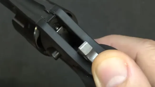 Close-up of a person's thumb on the cylinder release of a Ruger LCR revolver.