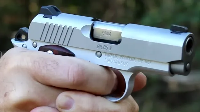Close-up of a Kimber Micro 9 pistol in hand, showing the slide's details and barrel with the caliber marking.